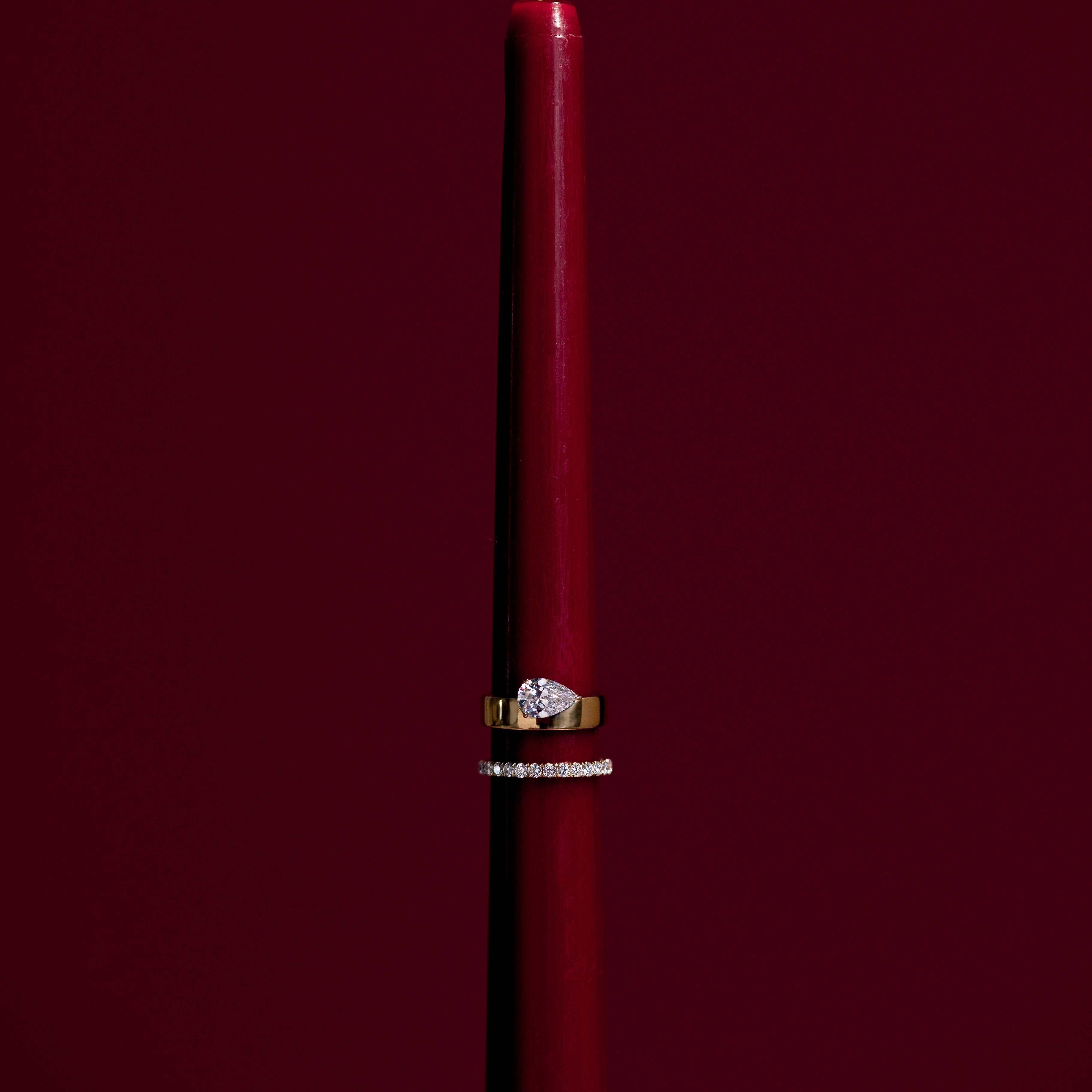 Red candle with a flame on a dark red background