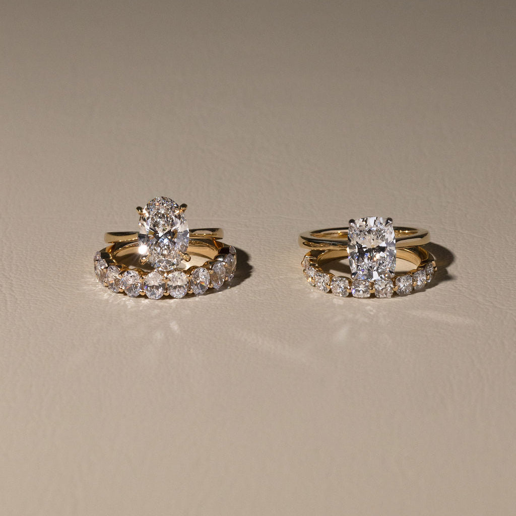 Two gold rings with diamond accents on a beige background