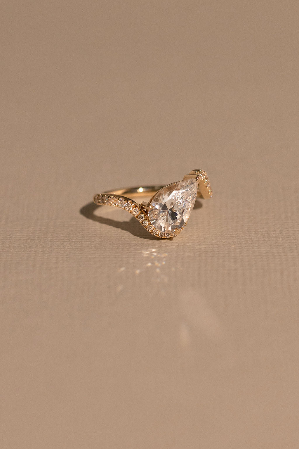 Gold ring with a large diamond on a beige background