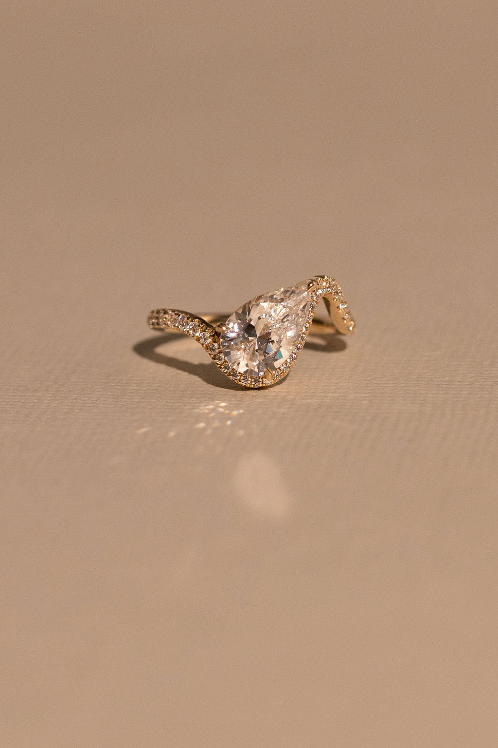 Gold ring with a large diamond on a beige background