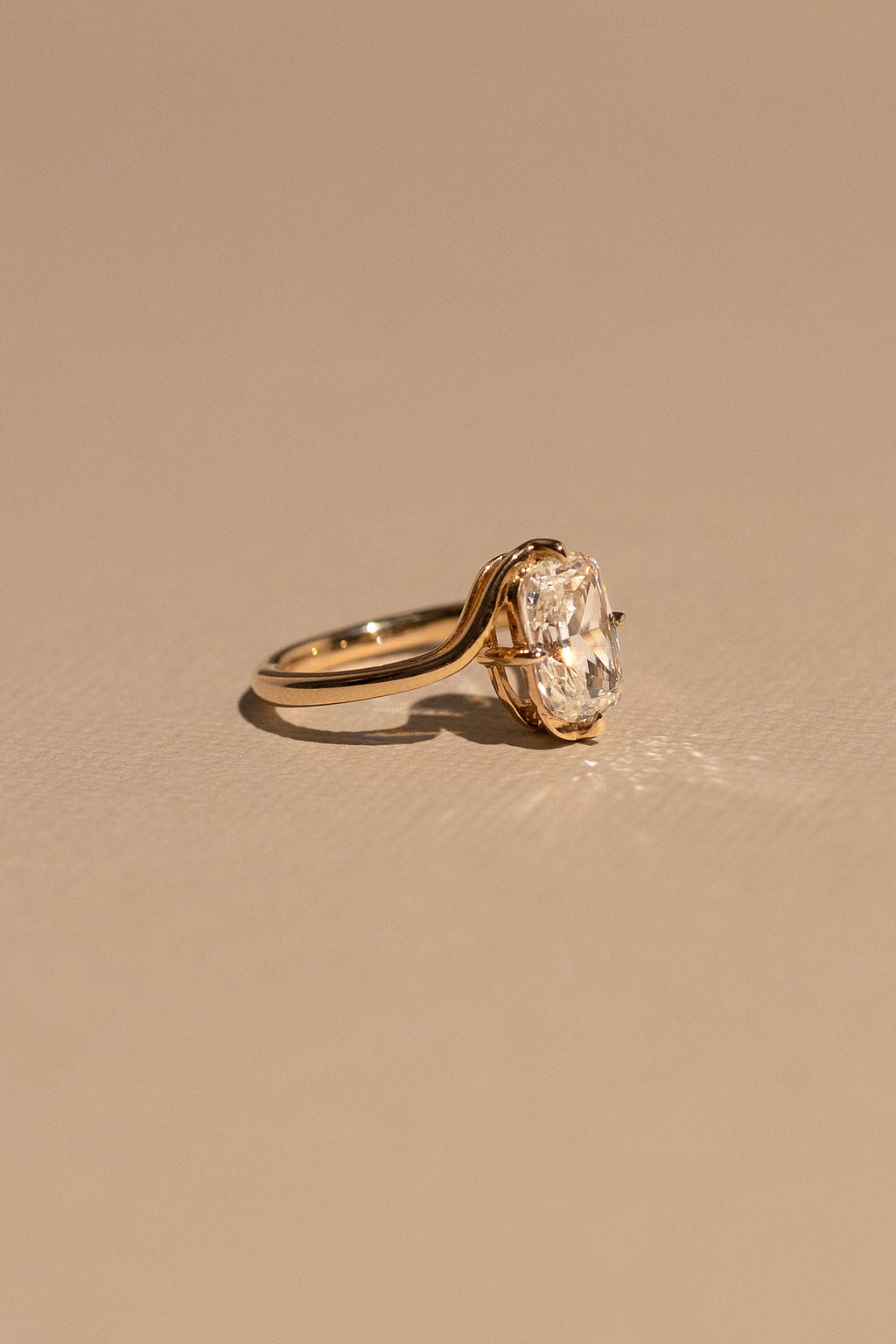 Gold ring with a large diamond on a beige background