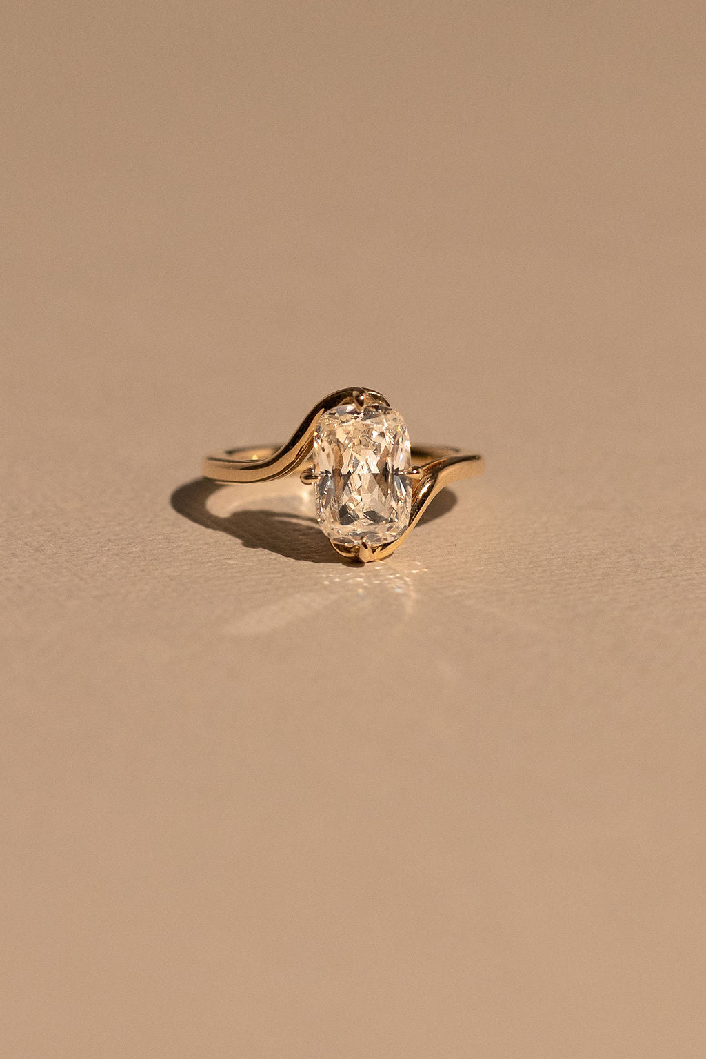 Gold ring with a diamond on a beige background