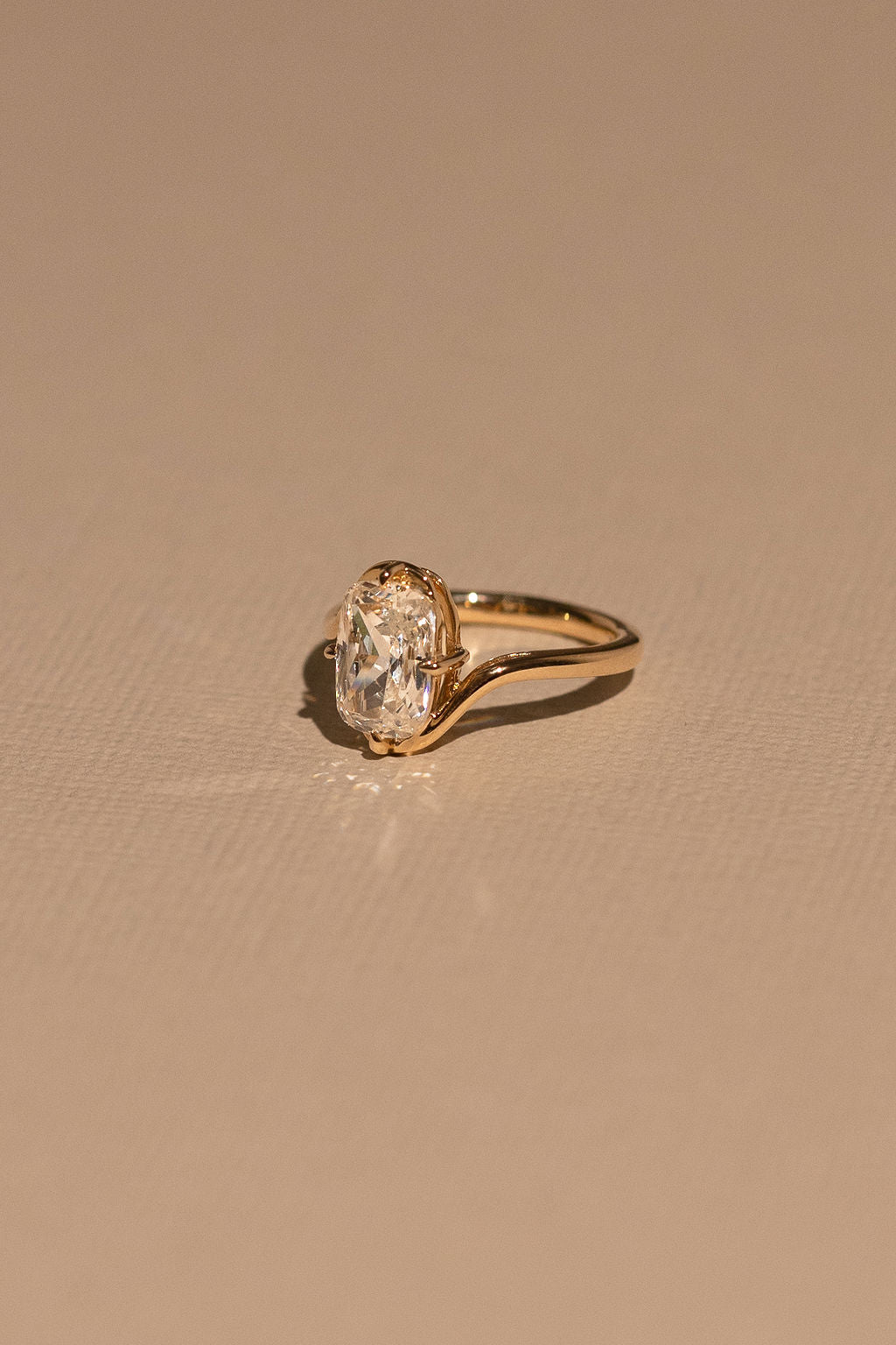 Gold ring with a diamond on a beige background