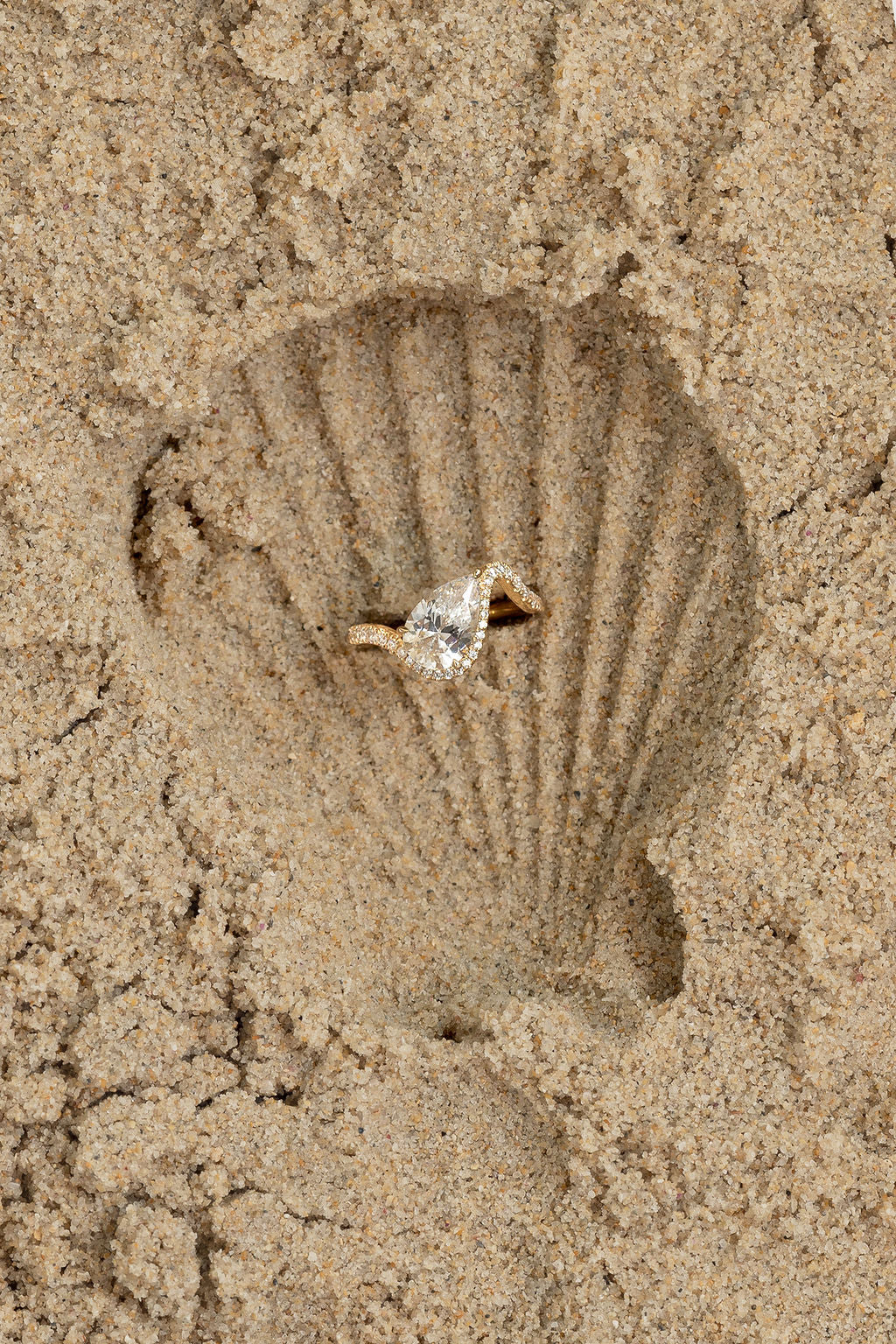 Diamond ring inside a shell-shaped sand impression on sand