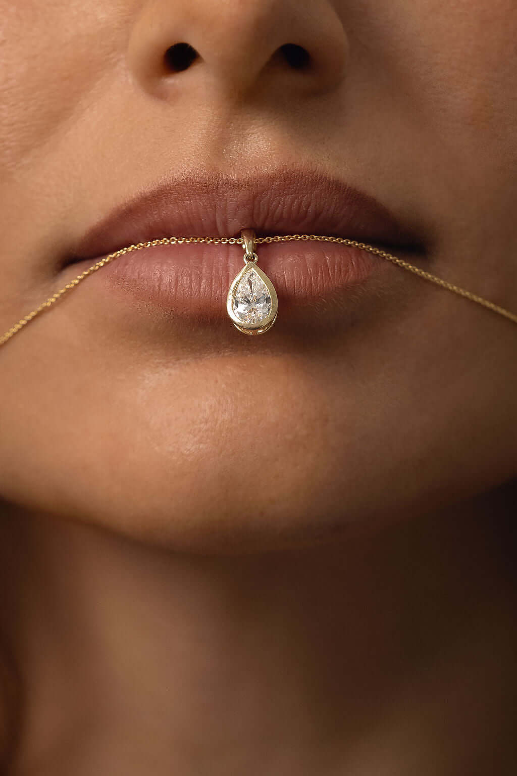 Close-up of a woman wearing a 1ct Pear Lab Diamond Bezel Pendant on a gold chain.