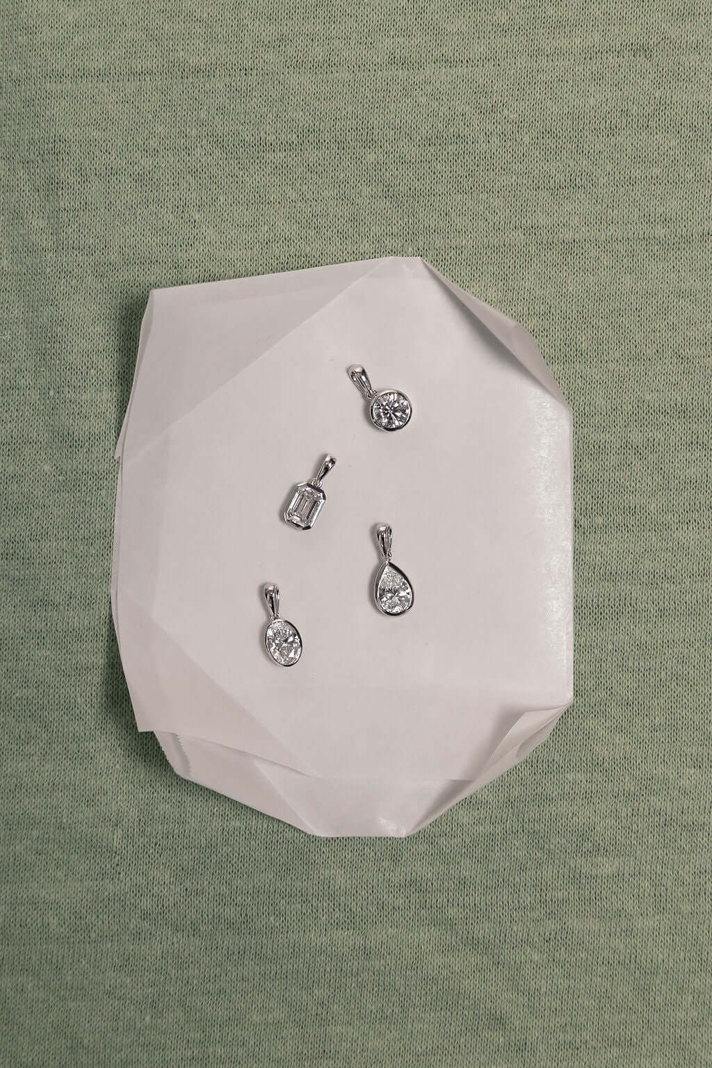 1ct Oval Lab Diamond Bezel Pendant on a white paper background showcasing elegant designs.