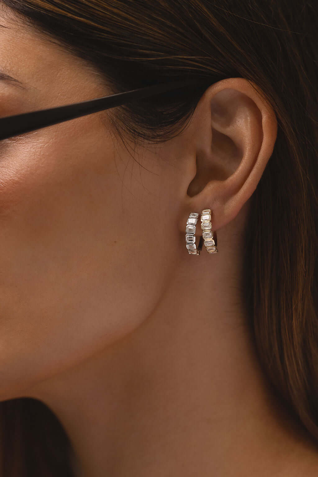 Emerald Bezel Hoop Earrings Lab Diamond worn on a woman's ear, showcasing the elegant design and sparkling lab diamonds.