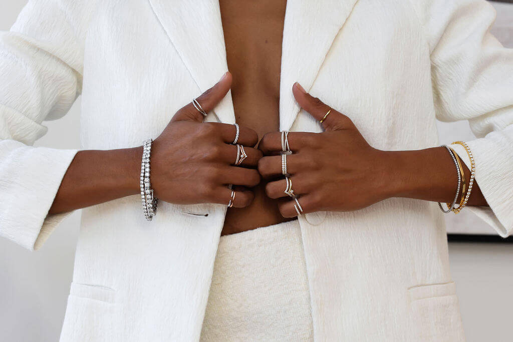 Black woman wearing jewellery on hand in white suit