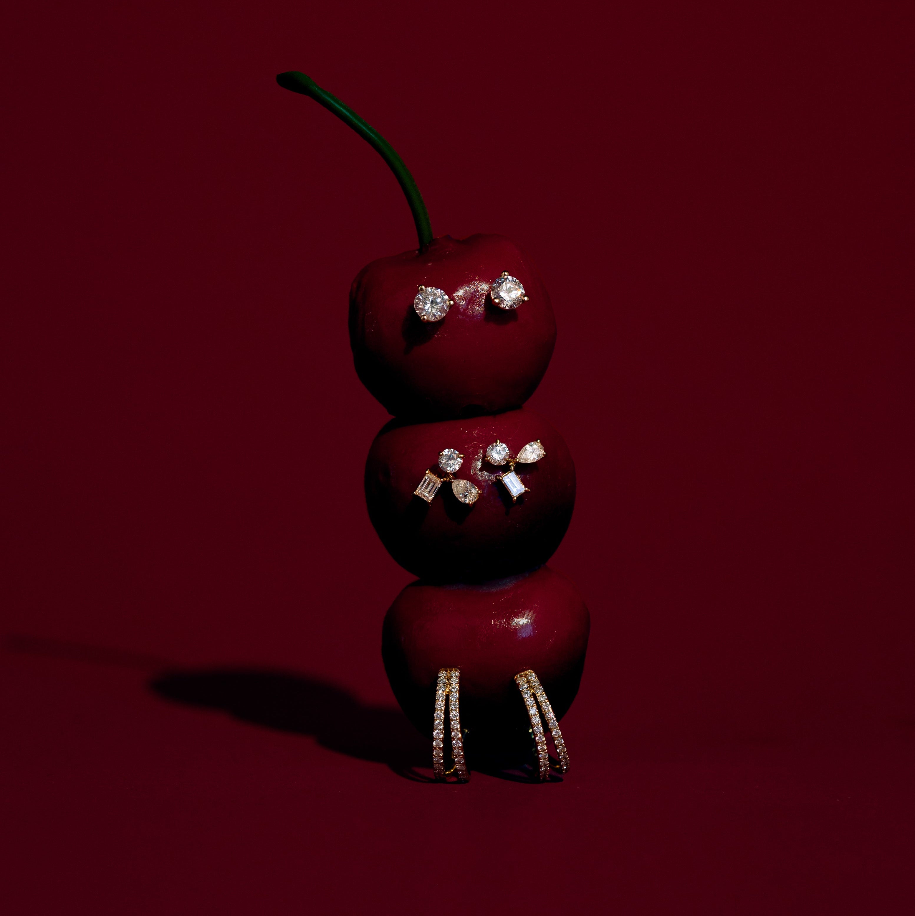 Three red cherries with decorative elements on a dark red background