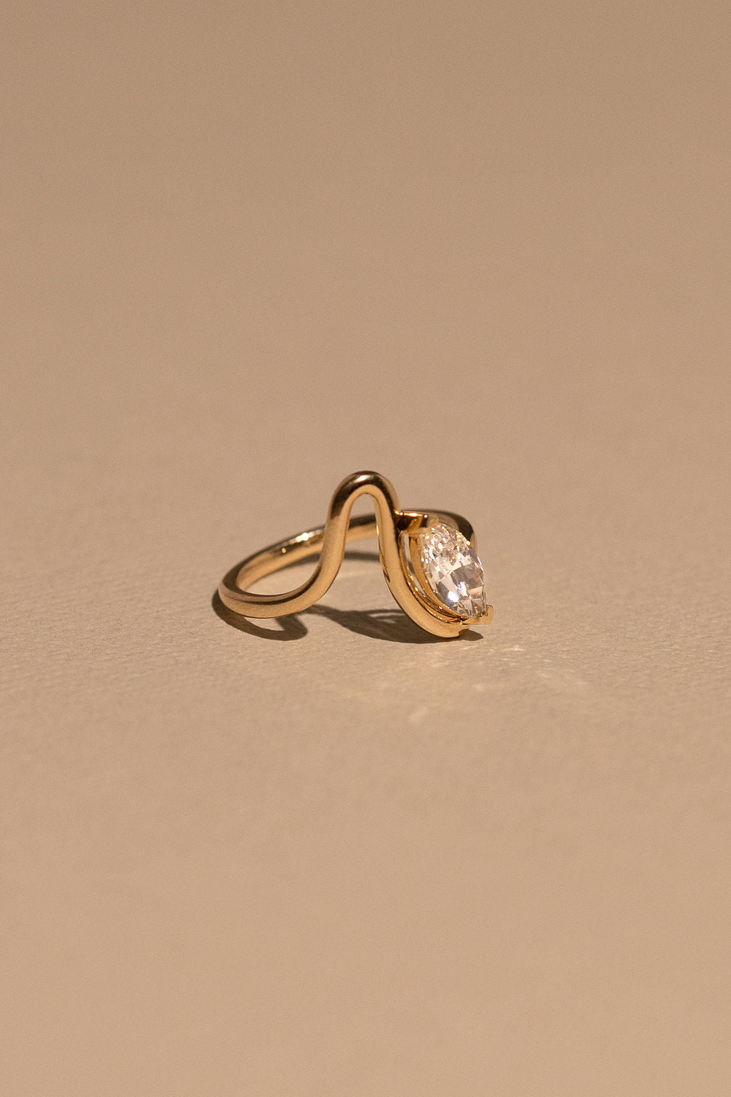 Gold ring with a diamond on a beige background