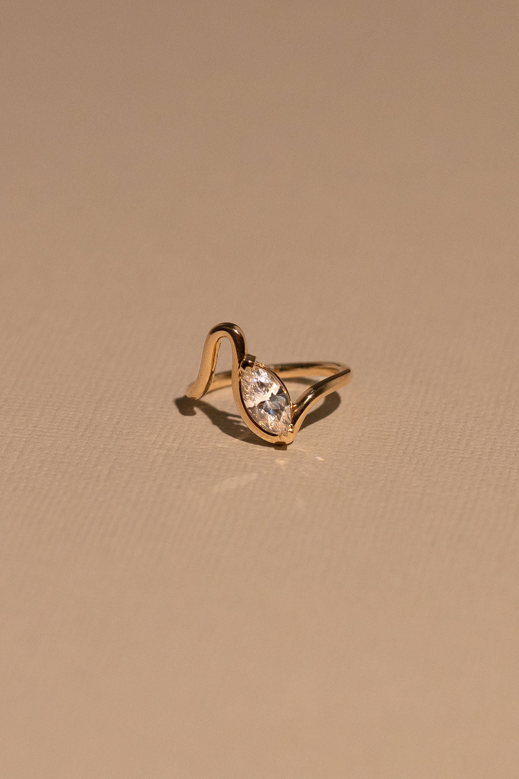 Gold ring with a diamond on a beige background