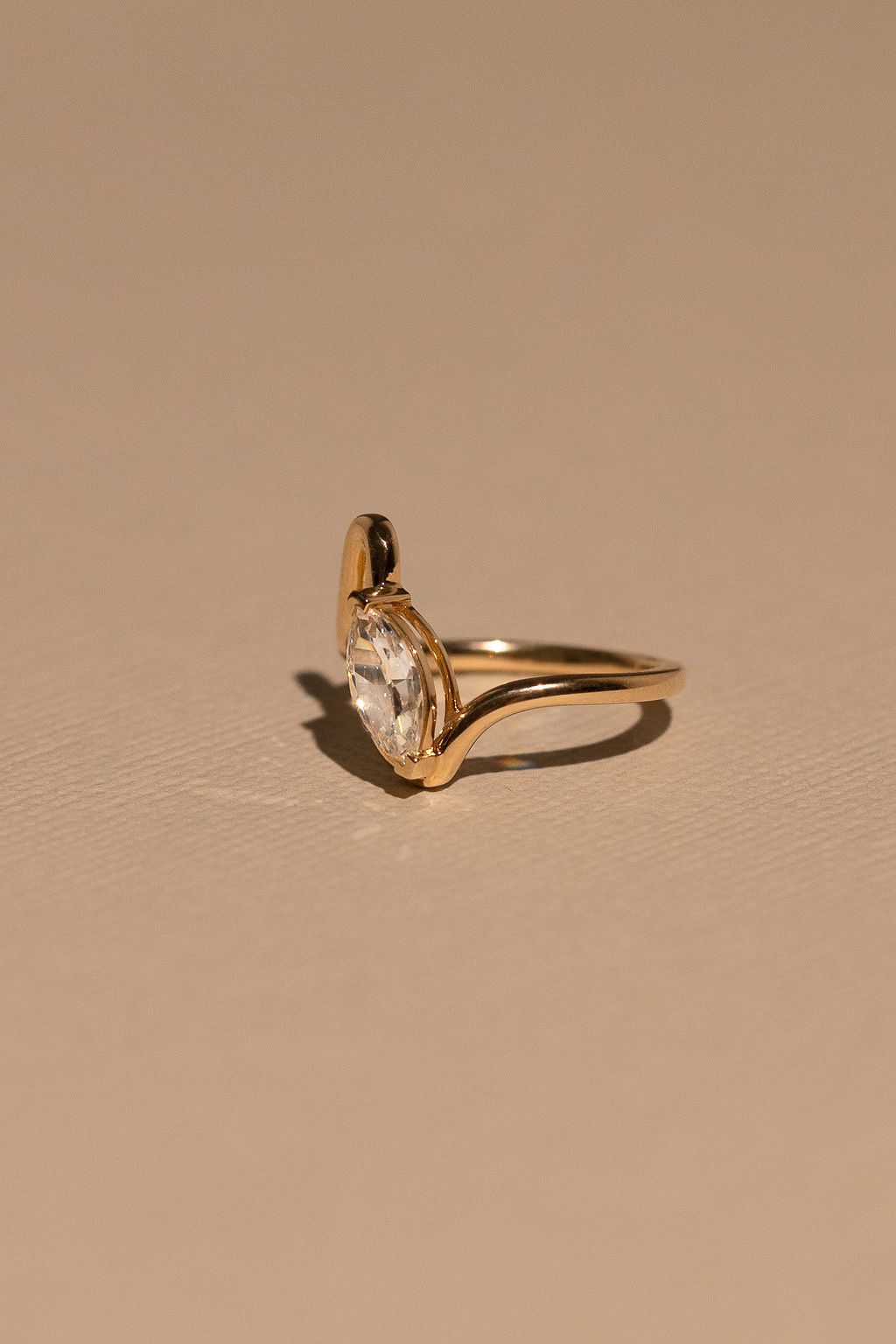 Gold ring with a clear gemstone on a beige background