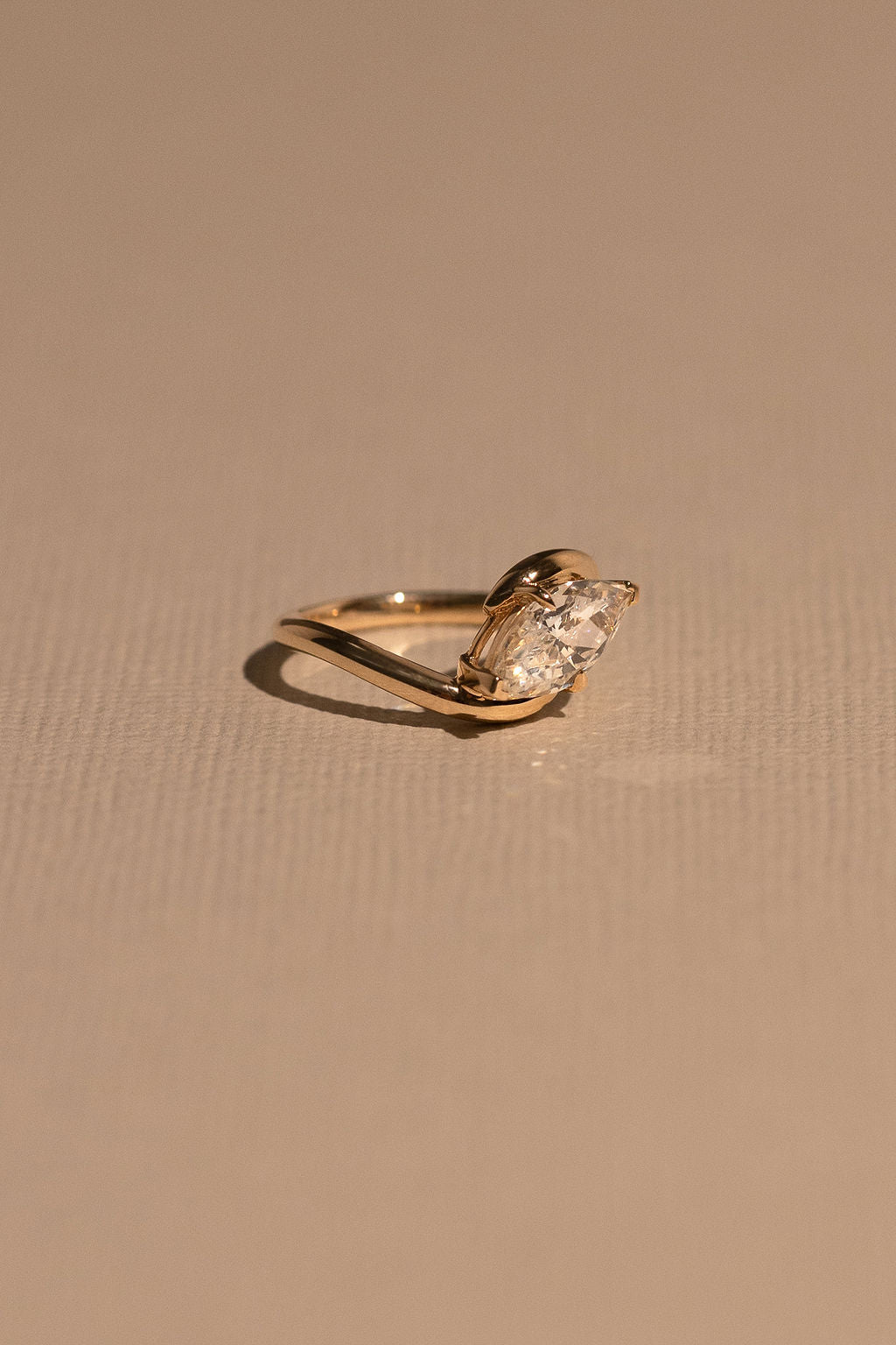 Gold ring with a diamond on a beige background