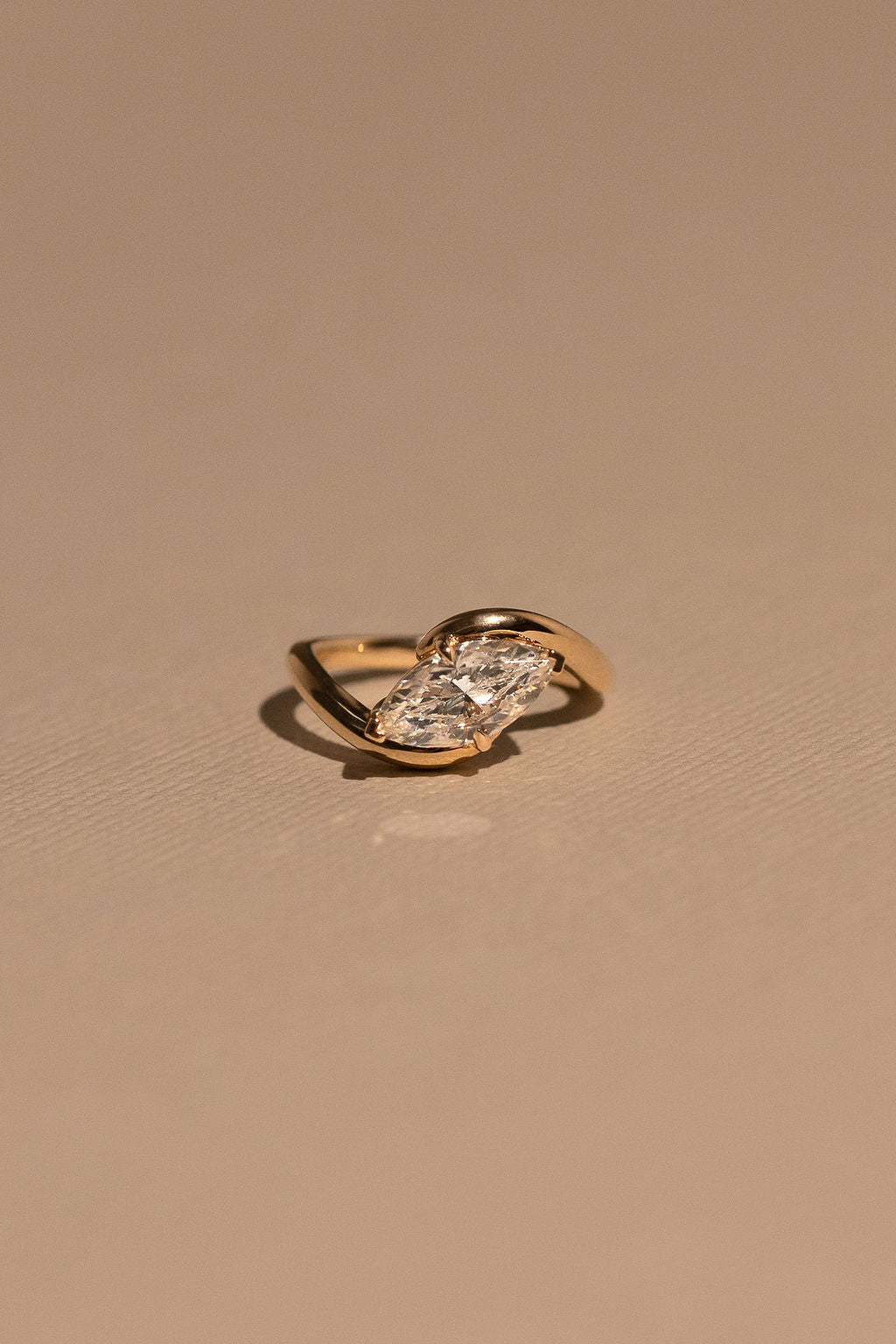 Gold ring with a diamond on a beige background