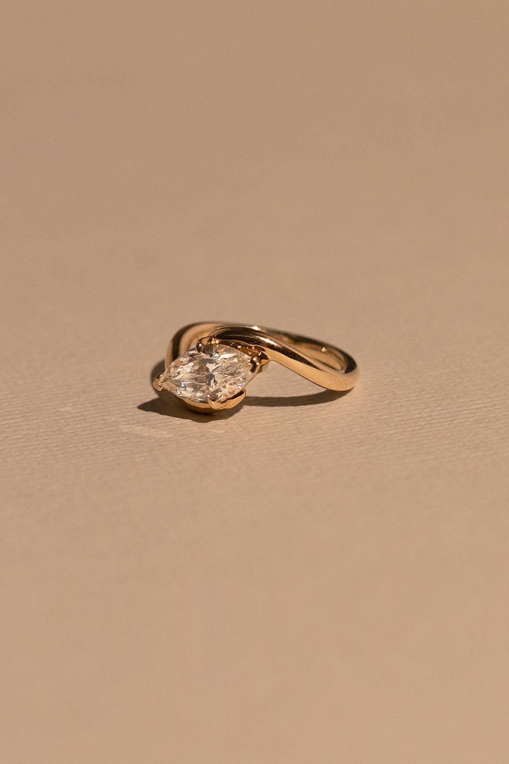 Gold ring with a diamond on a beige background