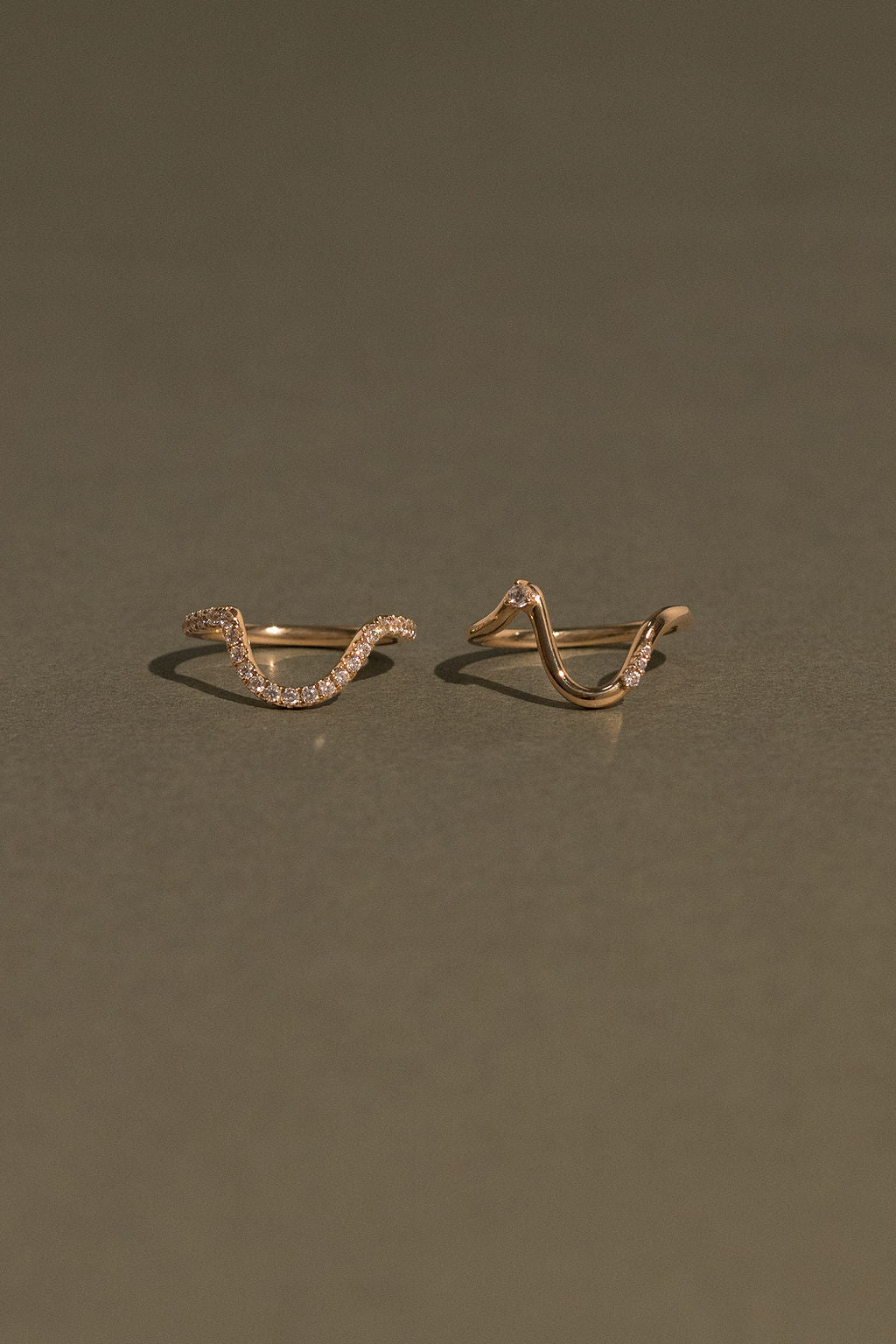 Two gold ring designs on a dark green background
