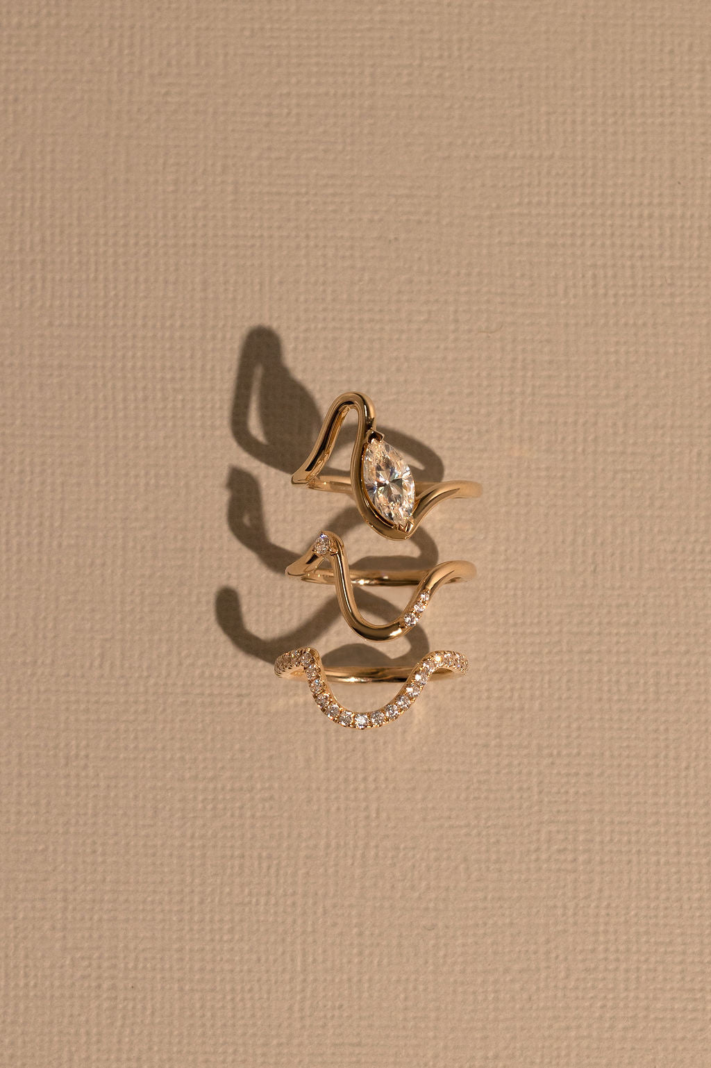 Three gold rings with gemstones on a beige background