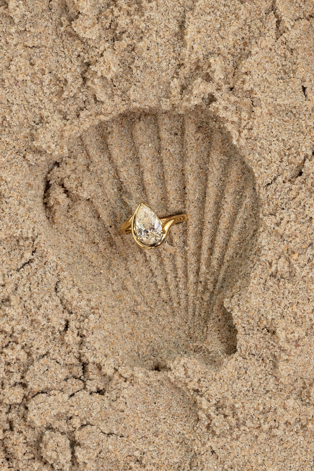 Gold ring with a diamond on a sand imprint of a shell