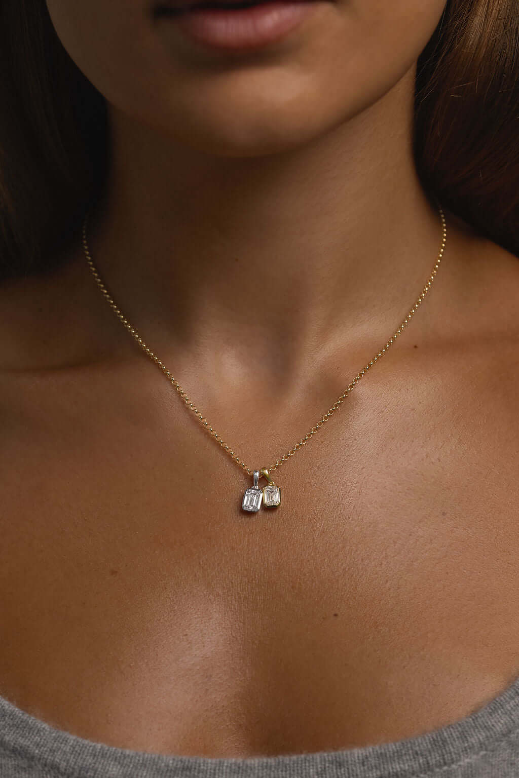 1ct Emerald Lab Diamond Bezel Pendant worn on a woman's neck, showcasing yellow gold and diamond details.