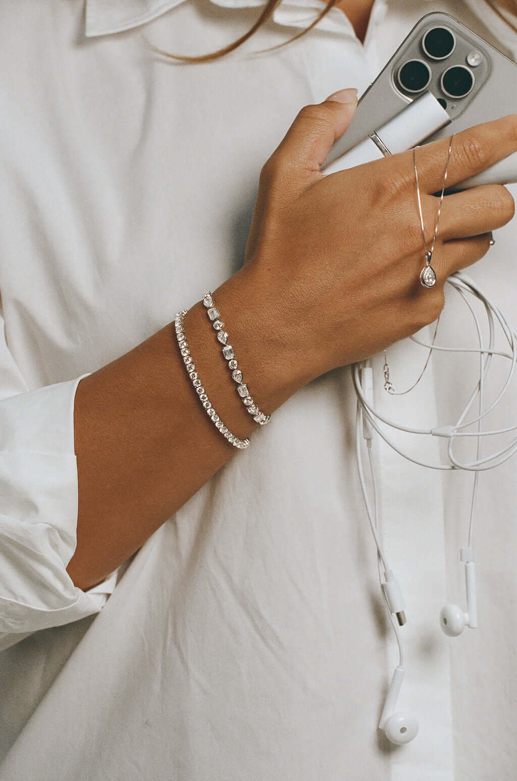 Elevated Round Tennis Bracelet 9.2ct Lab Diamond showcased on a hand, paired with a phone and earphones.